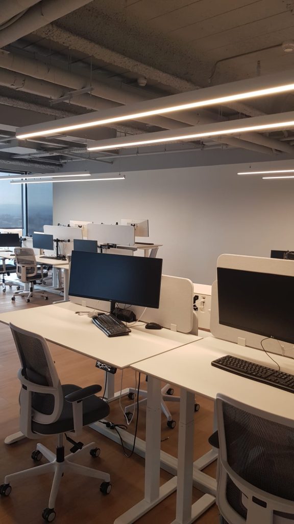 שולחנות עבודה עם מסכים וגופי תאורה מעל כל שורה.