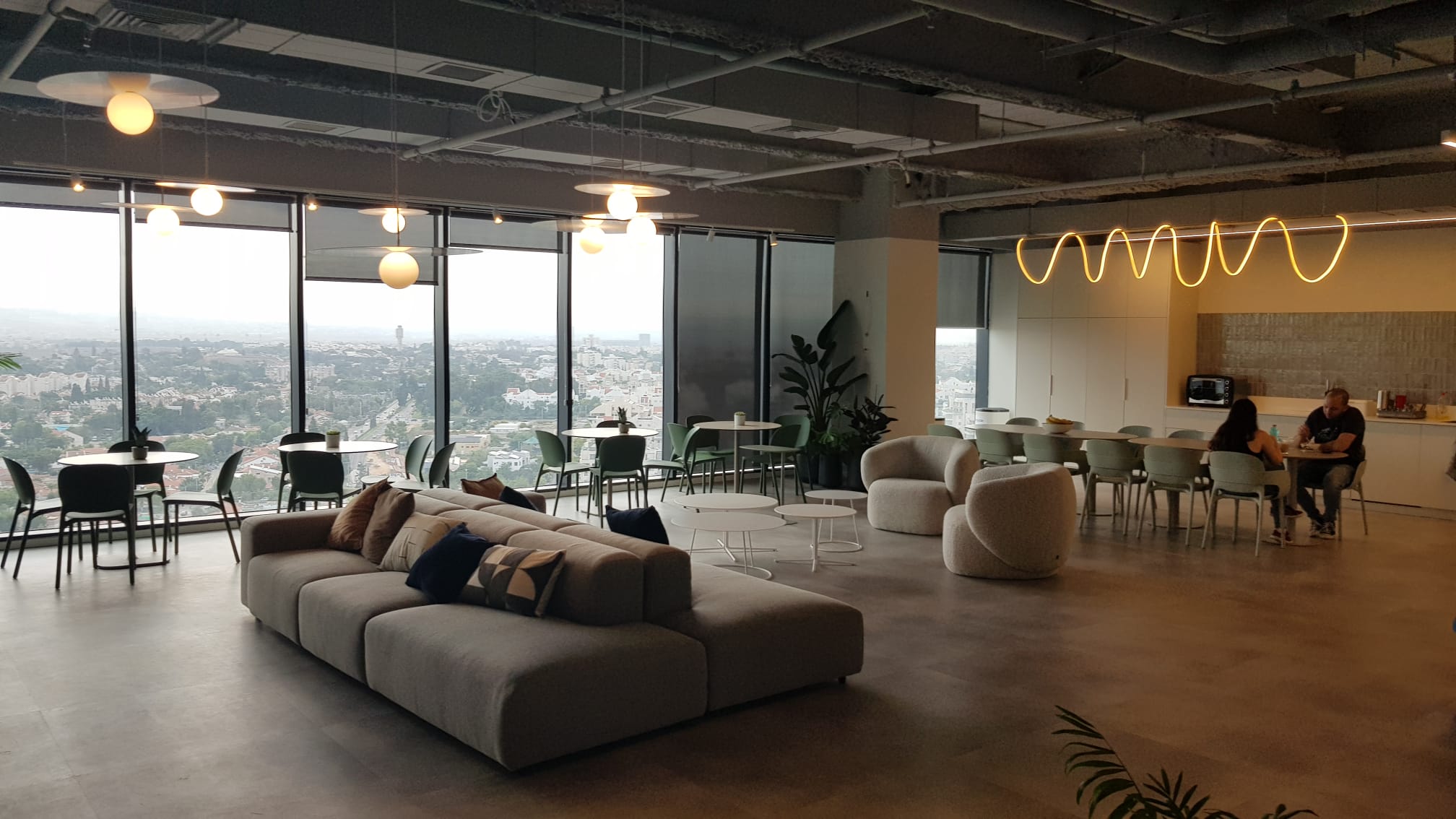 מבט כולל על חלל עבודה פתוח עם תאורה תלוית תקרה וקירות זכוכית.